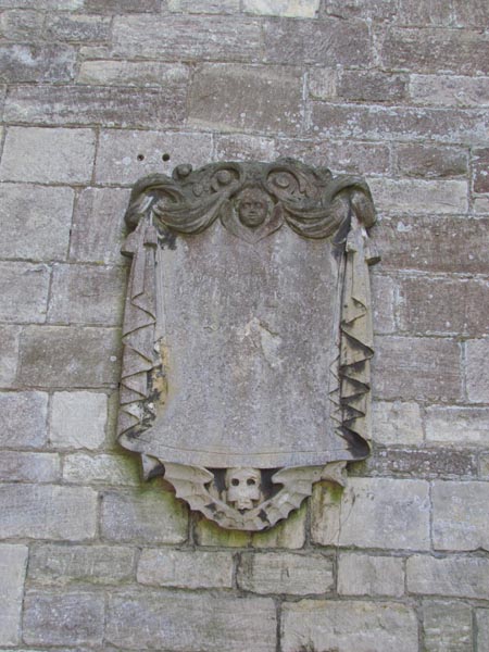 Small carved stone plaque with a face at the top and stone drapes either side.